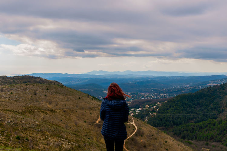 Rear view of woman standing on mountain against sky