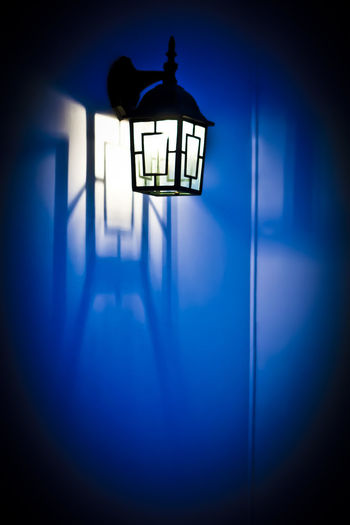 Illuminated lamp hanging on wall in building
