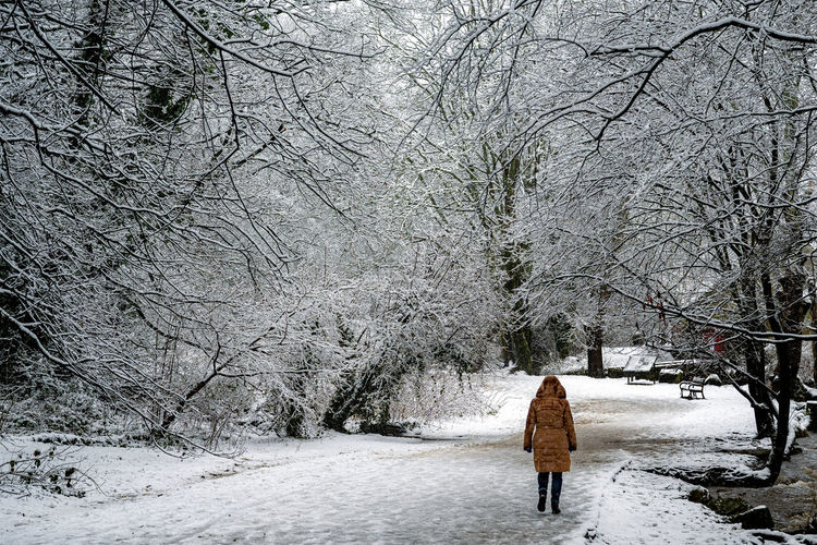 Rear view of woman walking on snow covered field