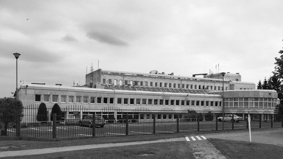 Empty road leading to built structure against sky