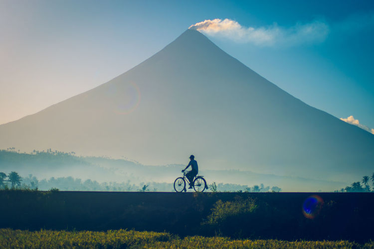 Man riding bicycle against mountain