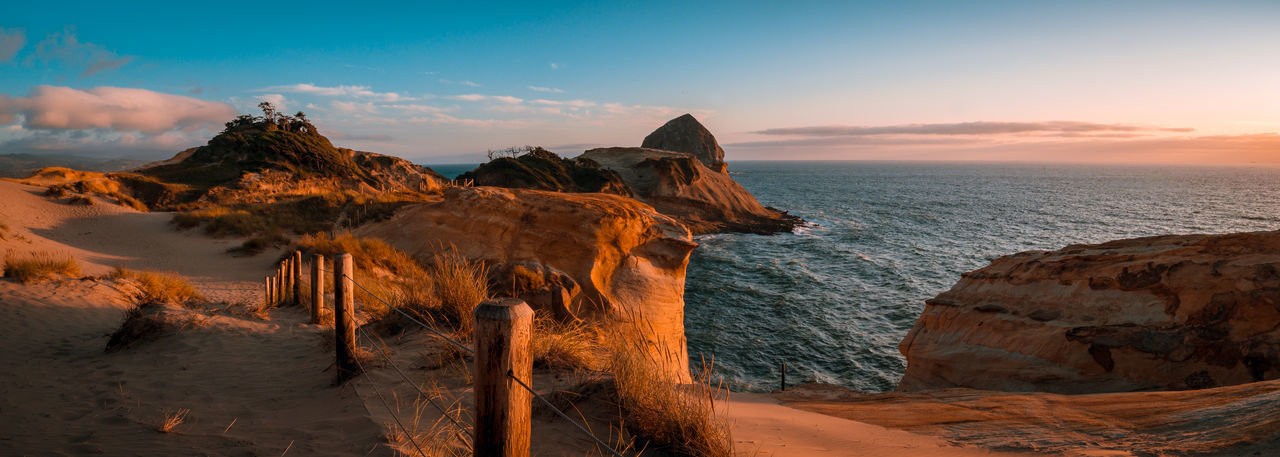Rock formations on shore against sky during sunset