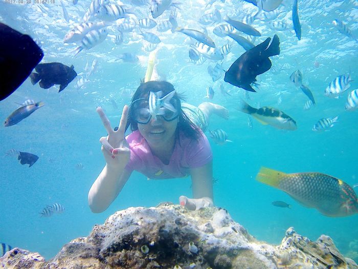 Carefree woman showing peace sign while swimming in sea
