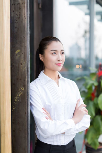 Smiling businesswoman with arms crossed standing outdoors