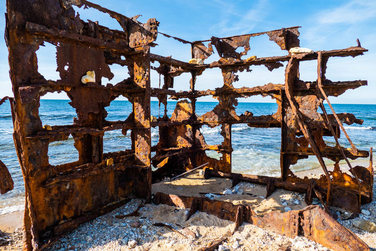 Old rusty metallic structure on sea shore against sky