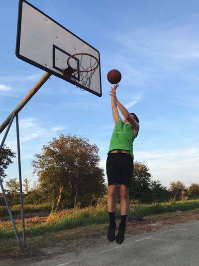 Man playing basketball against sky