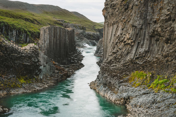 Studlagil basalt canyon, with rare volcanic basalt column formations and blue river. iceland.