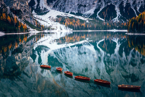 Boats in lake against snowcapped mountains