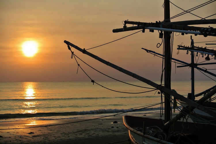 Rising sun in the sea and fishing boat on beach at hus hin , thailand.