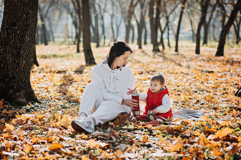 Happy family mother and little toddler baby daughter having fun together in autumn picnic