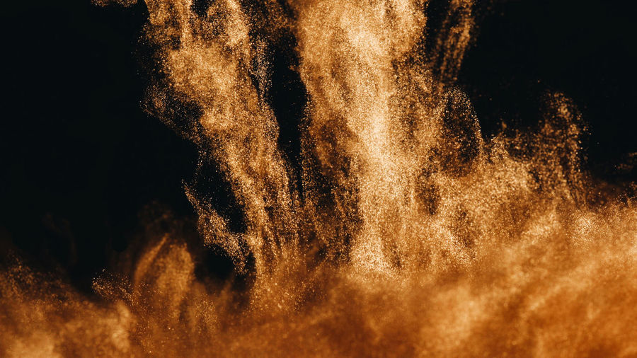 Close-up of golden ink in water against black background