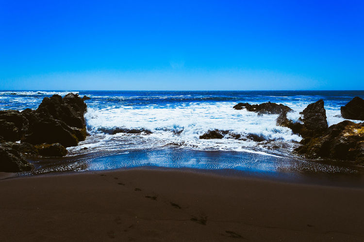 Scenic view of beach against clear blue sky