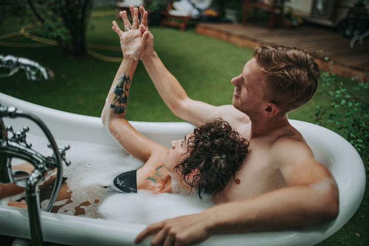 Rear view of shirtless boy and woman in water
