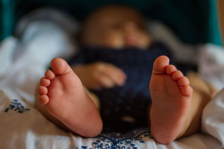 Close-up of baby relaxing on bed at home