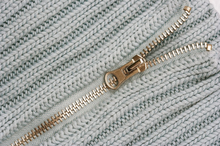 Close-up of zipper on white sweater