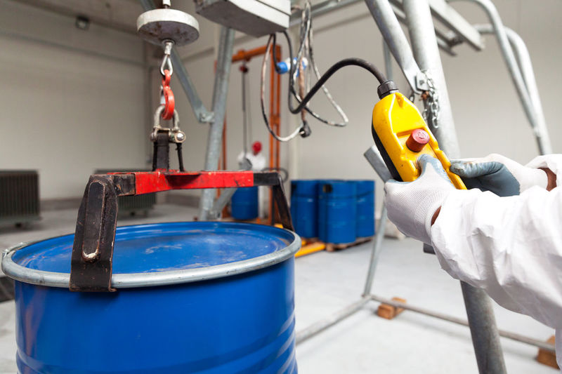 Cropped image of worker using drum lifter in warehouse