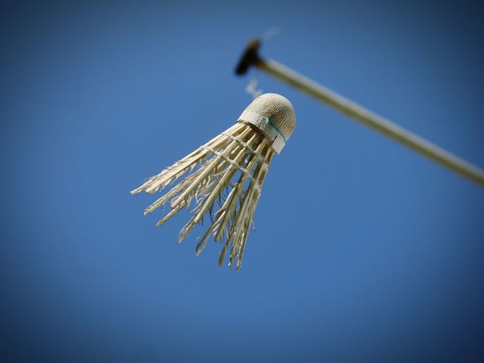 Low angle view of shuttlecock against clear blue sky