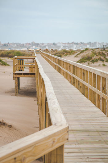 Wooden boardwalk on beach against sky