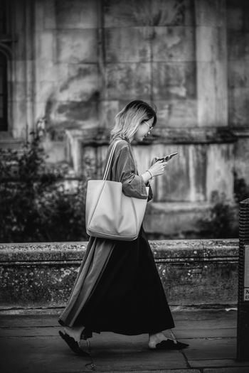 Woman holding umbrella while standing on mobile phone