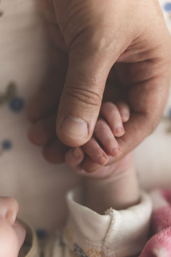 Close up of newborn baby holding dad's finger