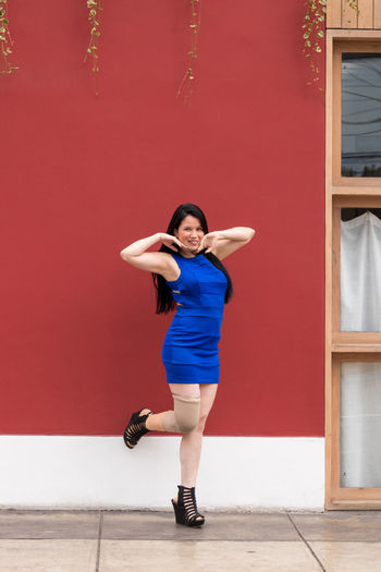 Full length of woman using standing against red wall