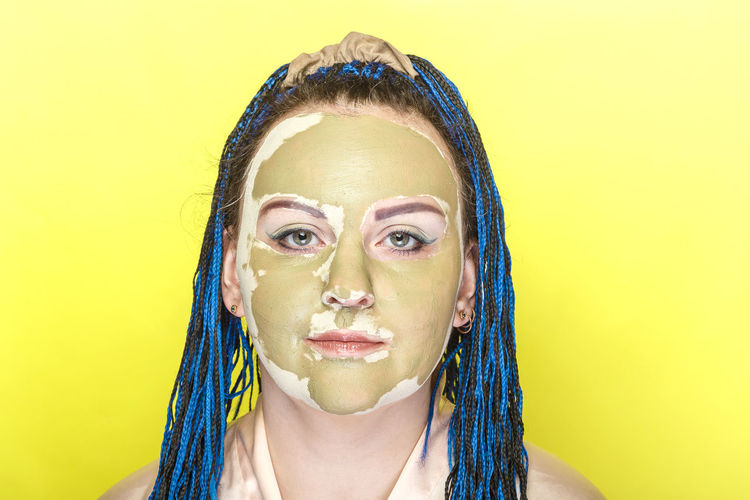 Portrait of woman wearing mask against yellow background