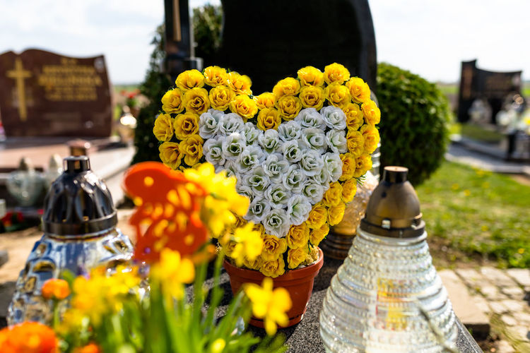Artificial flowers in the shape of a heart and candlesticks lie on the tombstone in the cemetery.