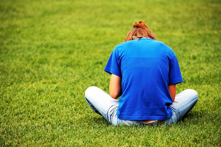 Rear view of woman sitting on grassy field