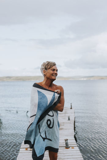 Smiling woman wrapped in towel at sea