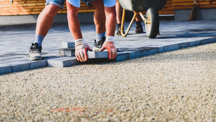 Construction worker arranging paving stones on street