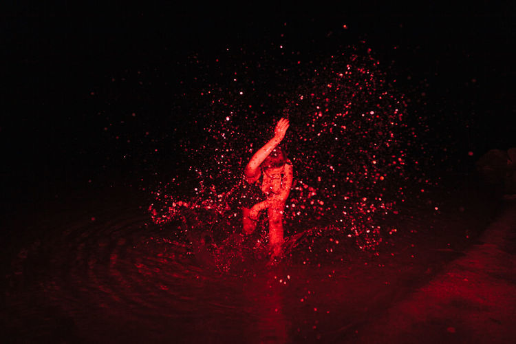 Woman splashing water in sea at night