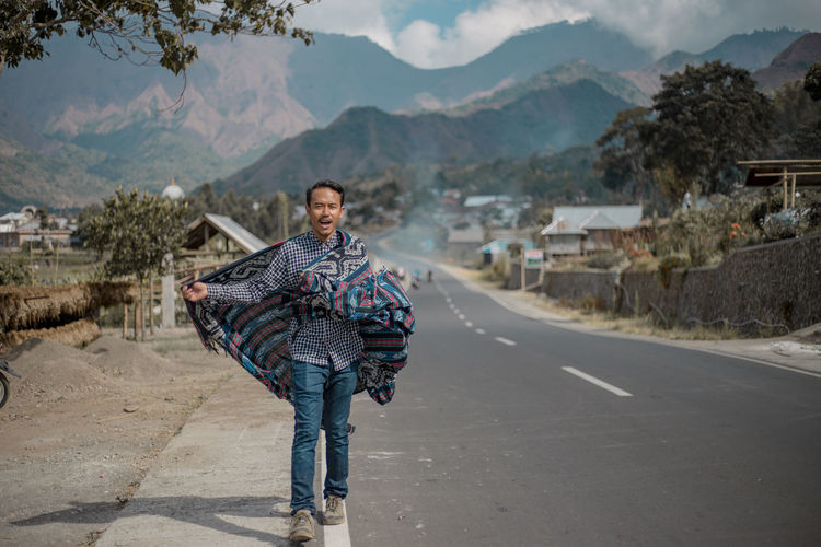 Portrait of man walking on road against mountains