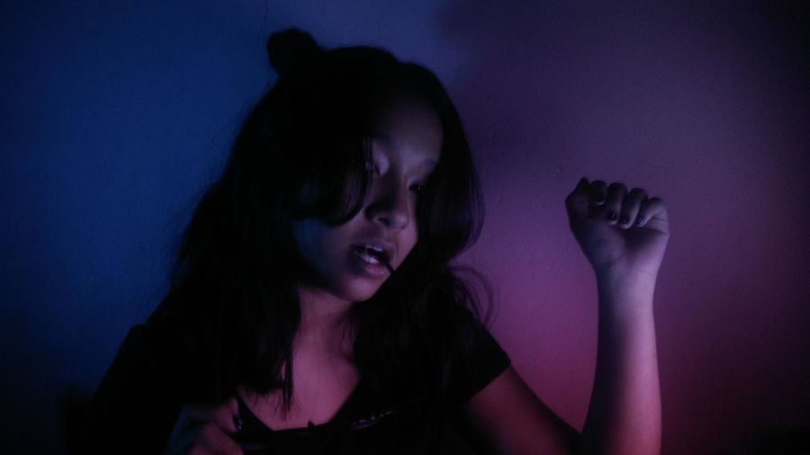 Teenage girl dancing against illuminated wall