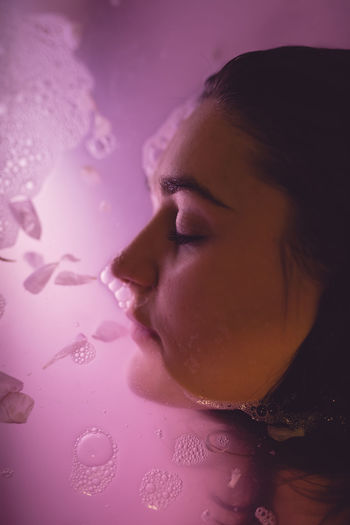 Close-up of young woman in pink water