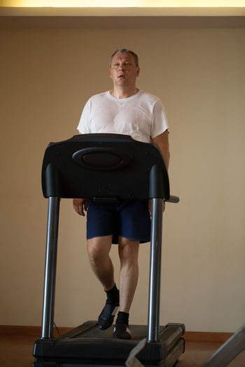 Full length of man walking on treadmill at home