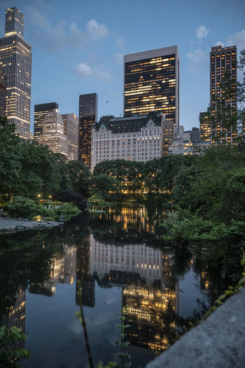 Reflection of illuminated buildings in city at night central park