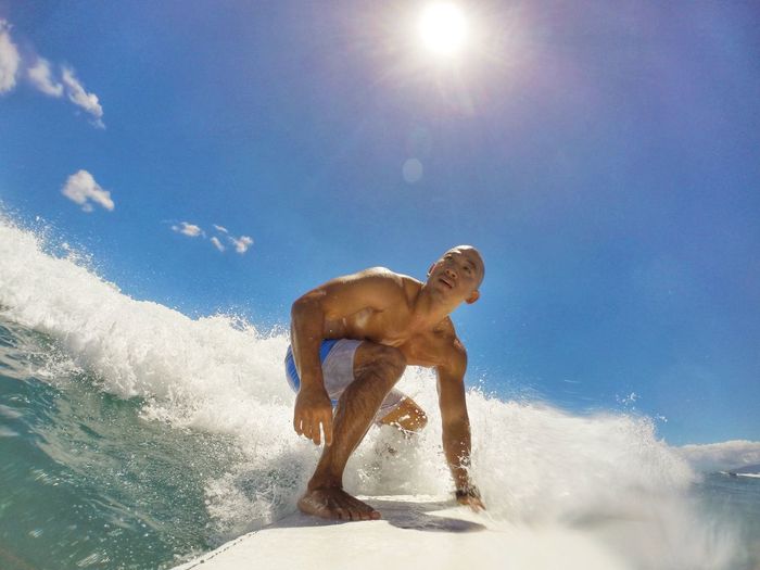 Shirtless man surfing on breaking wave