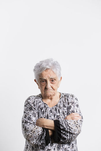 Portrait of angry senior woman in front of white background