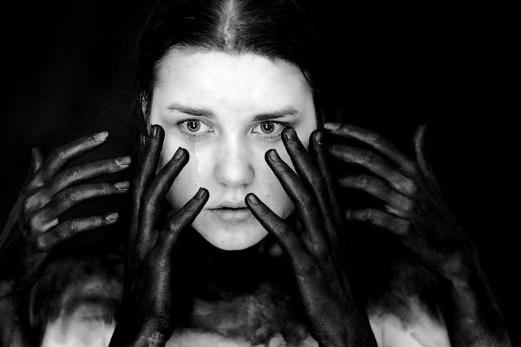Portrait of woman with hand on black background
