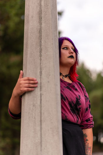 Portrait of young woman standing against lamppost 
