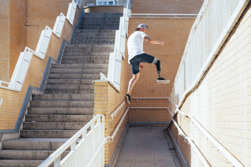 Young man with leg prosthesis performing parkour in the city