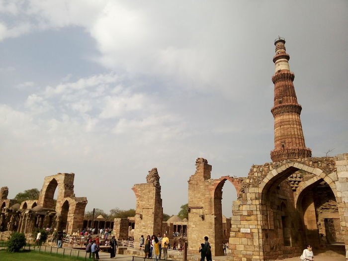 Low angle view of qutub minar against cloudy sky