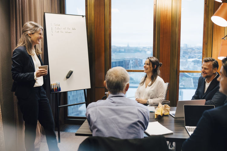 Smiling female lawyer giving presentation to colleagues in board room at office