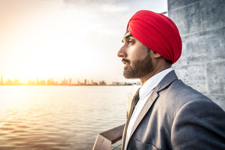 Businessman wearing turban looking away while standing by river