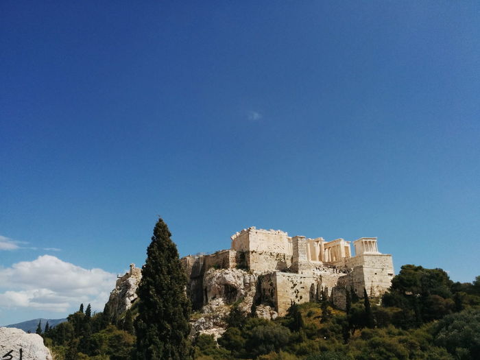 Low angle view of acropolis temple on hill against sky