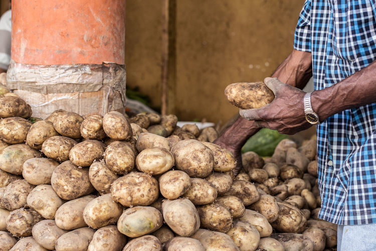 Midsection of male vendor selling potatoes at market