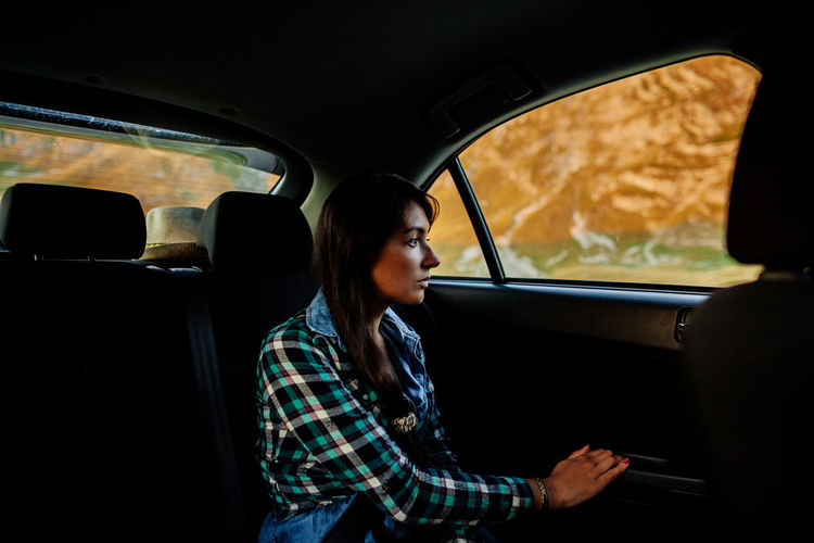 Young woman looking through car window
