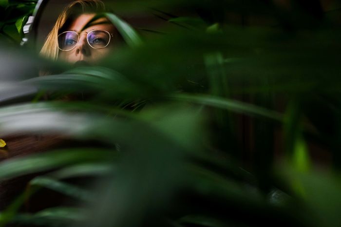 Thoughtful woman wearing eyeglasses seen through plants