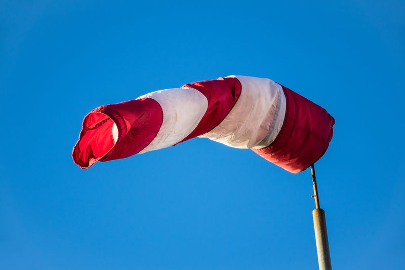 Low angle view of windsock against clear blue sky during sunny day