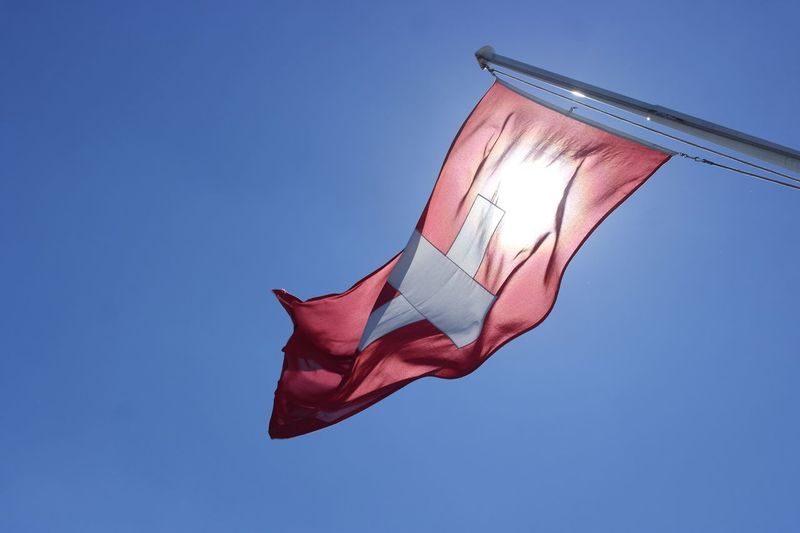 Low angle view of swiss flag against blue sky
